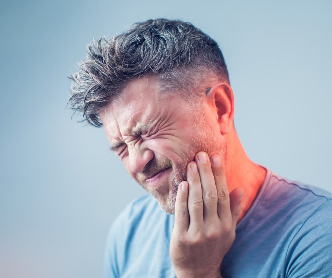 man grabbing his jaw due to pain